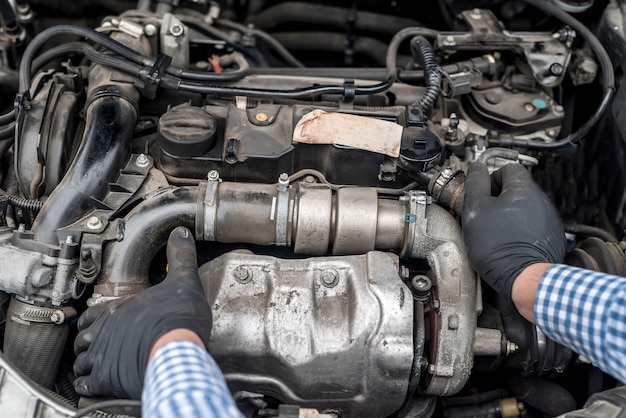 Il motore di automobile con le mani dell'operaio si chiuda