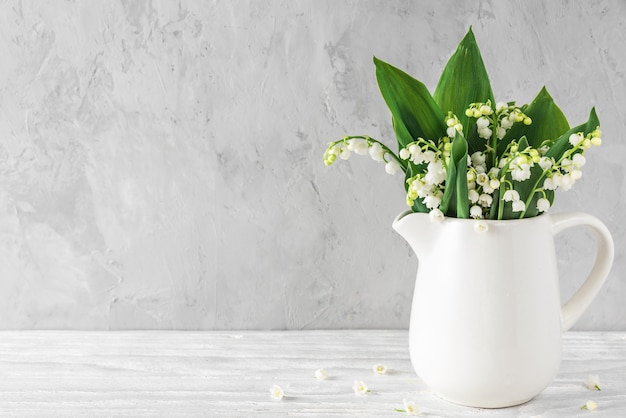 Il mughetto della primavera fiorisce in vaso su fondo concreto con lo spazio della copia. natura morta