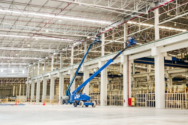 Il muratore viene sollevato dal boom lift fino alla gronda di un edificio industriale sotto co