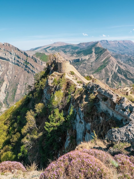 Il muro della vecchia fortezza sulla collina contro il cielo blu. La fortezza di Gunib è un monumento storico del Daghestan. Vista verticale.