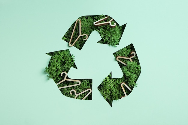 Il muschio verde e gli appendiabiti sotto la carta tagliano il simbolo del riciclaggio Salva il concetto di panno per il riciclaggio del pianeta
