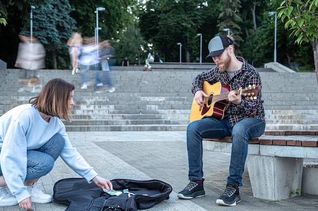 Il musicista di strada maschio suona la chitarra acustica