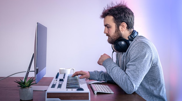 Il musicista maschio crea musica utilizzando il computer e il posto di lavoro del musicista della tastiera