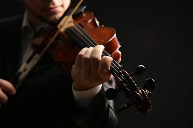 Il musicista suona il violino su sfondo nero da vicino