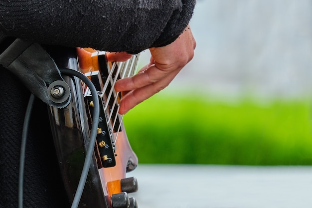 Il musicista tiene una chitarra di strumento musicale e suona per strada.