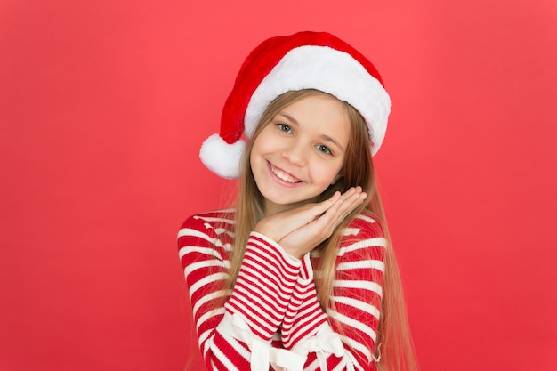 Il Natale è tempo di compiacere Il bambino felice indossa il costume di Natale sfondo rosso Bambina piccola