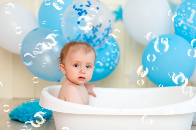 Il neonato bagna in una vasca con palloncini e bolle di sapone, infanzia felice, compleanno dei bambini