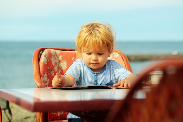 Il neonato carino legge la carta del menu