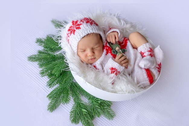 Il neonato dorme in accessori natalizi su sfondo bianco, il concetto di Natale e Capodanno