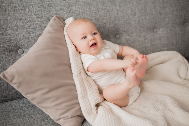 Il neonato in buona salute si trova sul sofà con un plaid molle. Il comfort del bambino a casa