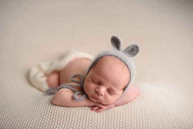 Il neonato in un cappello tricottato dorme su una coperta a maglia leggera.