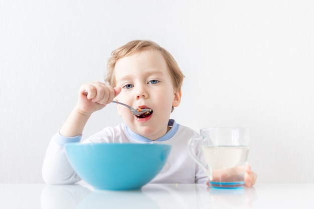 Il neonato mangia con un cucchiaio a casa il concetto di cibo e nutrizione per i bambini