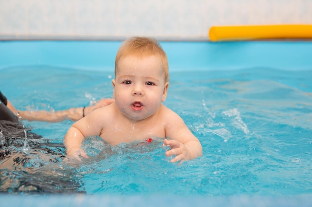 Il neonato si allena per nuotare in piscina con un allenatore