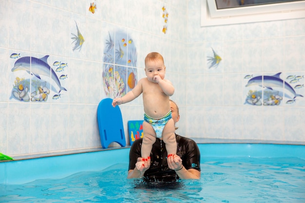 Il neonato si allena per nuotare in piscina con un allenatore