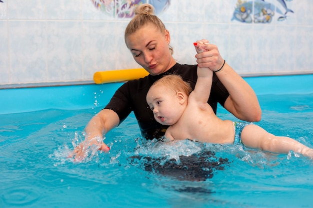 Il neonato si allena per nuotare in piscina con un allenatore