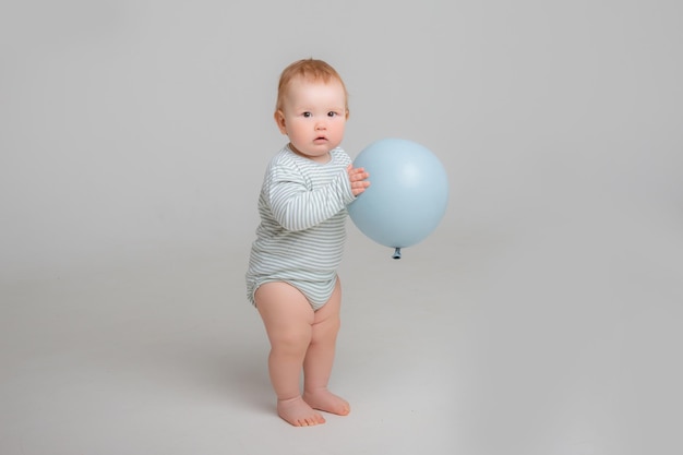 Il neonato sta tenendo un pallone su uno sfondo bianco