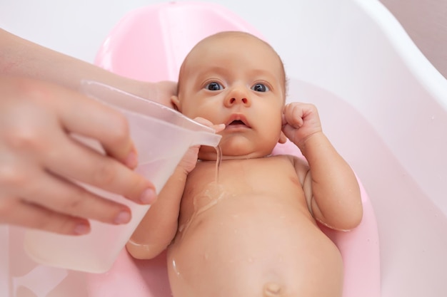 il neonato viene lavato in bagno, il bambino viene annaffiato con l'acqua di un secchio d'acqua