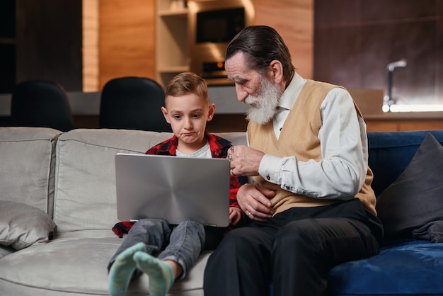 Il nipote sta insegnando a suo nonno a usare il computer portatile.