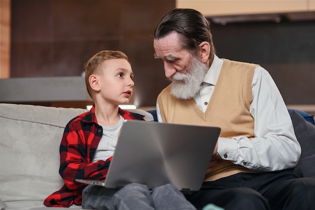 Il nipote sta insegnando a suo nonno a usare il computer portatile