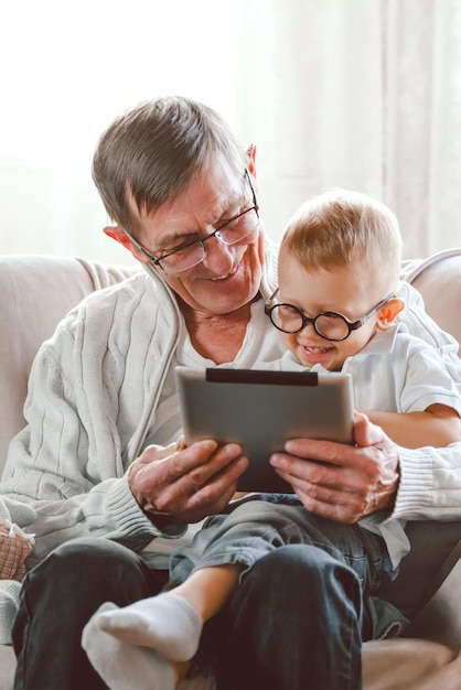 Il nonno anziano e il suo nipotino usano insieme un tablet