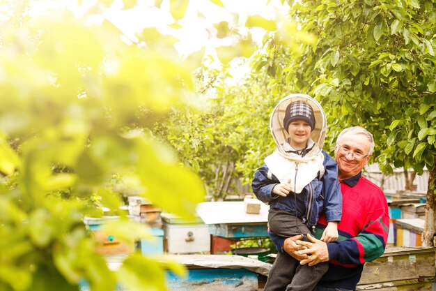 Il nonno apicoltore esperto insegna a suo nipote a prendersi cura delle api. Apicoltura. Il concetto di trasferimento di esperienza