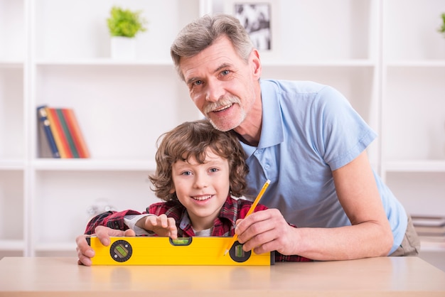 Il nonno con il nipote misura il livello del tavolo.