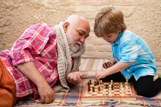 Il nonno e il nipote belli giocano a scacchi mentre trascorrono del tempo insieme a casa d'infanzia...