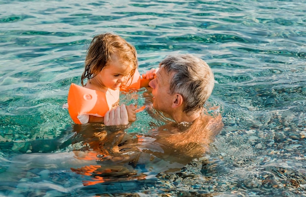 Il nonno e le ragazze nuotano in piscina.