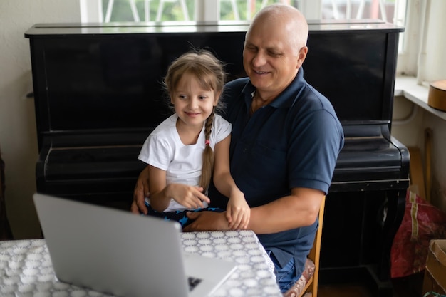 Il nonno e sua nipote usano un laptop insieme.