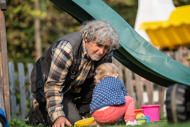 Il nonno gioca con sua nipote fuori nel parco giochi