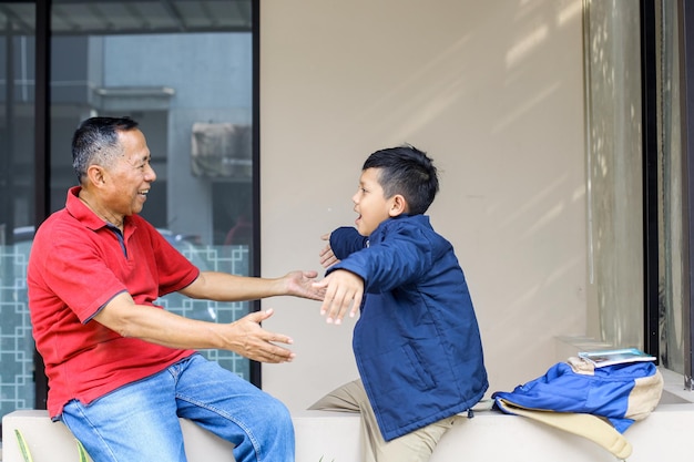 Il nonno gioca con suo nipote dopo la scuola e vogliono abbracciarsi Genitori e papà