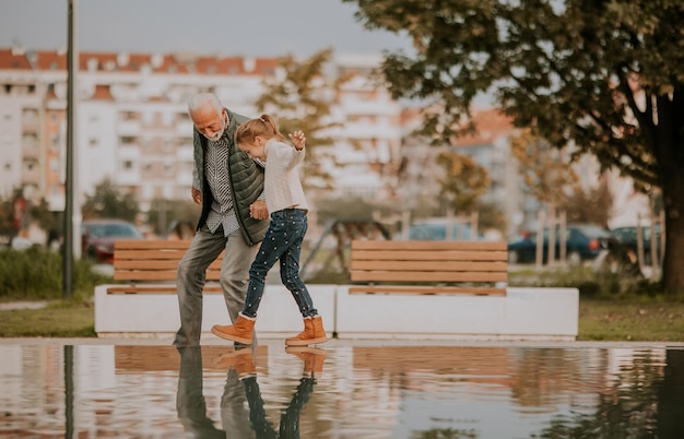 Il nonno trascorre del tempo con sua nipote presso una piccola piscina d'acqua nel parco il giorno d'autunno