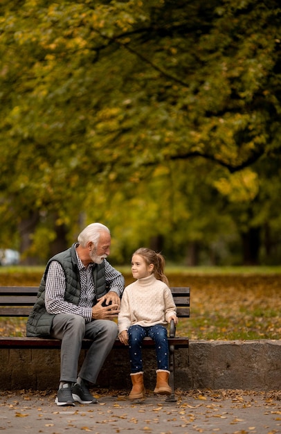 Il nonno trascorre del tempo con sua nipote sulla panchina nel parco il giorno d'autunno