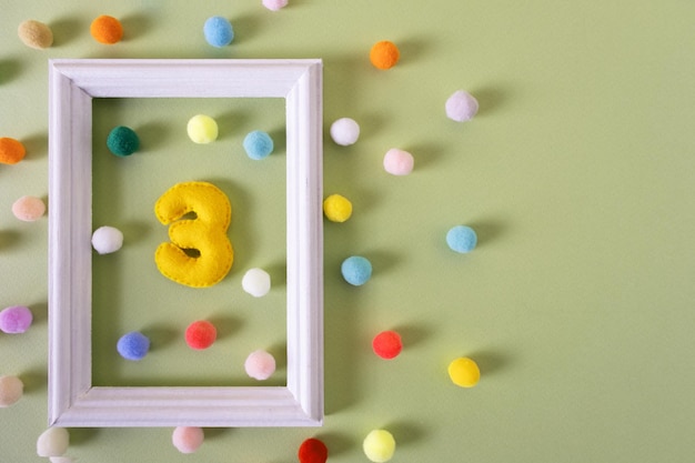 Il numero Tre per un compleanno in una cornice bianca con palline colorate Anniversario festivo di una festa da concerto