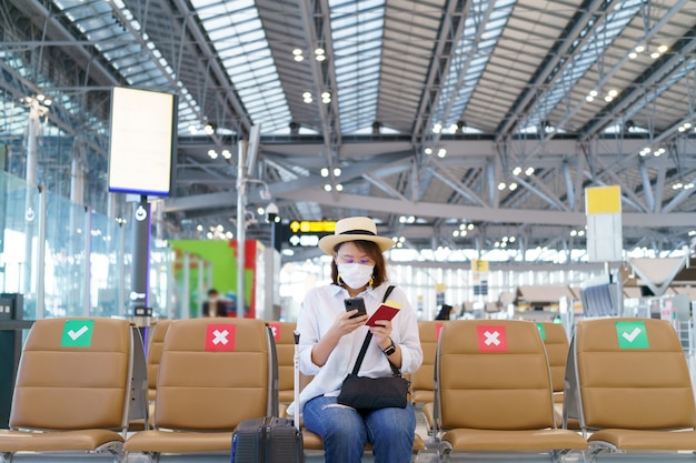 Il nuovo turista normale che indossa la maschera per il viso sta viaggiando in aeroporto