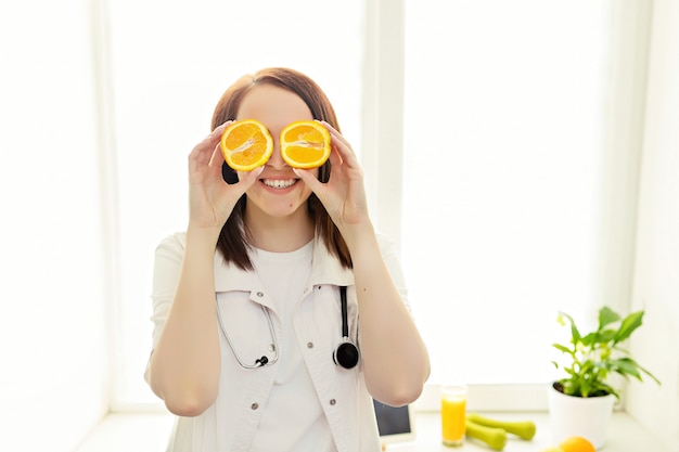 Il nutrizionista medico femminile tiene le arance davanti ai suoi occhi