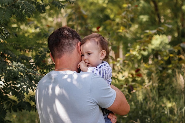 Il padre abbraccia il suo piccolo figlio La paternità della festa del papà Bambino sotto la protezione del padre