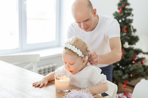 Il padre aiuta a mettere l'impianto cocleare per la sua bambina sorda nello spazio della copia del soggiorno di Natale Apparecchi acustici e tecnologie mediche innovative per il trattamento del concetto di sordità