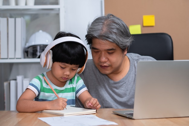 Il padre asiatico lavora a casa con una figlia e studia insieme a scuola online.