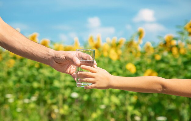 Il padre dà al bambino acqua sullo sfondo del campo