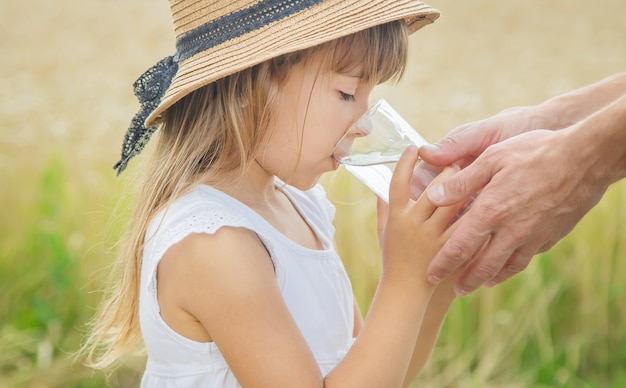 Il padre dà al bambino acqua sullo sfondo del campo