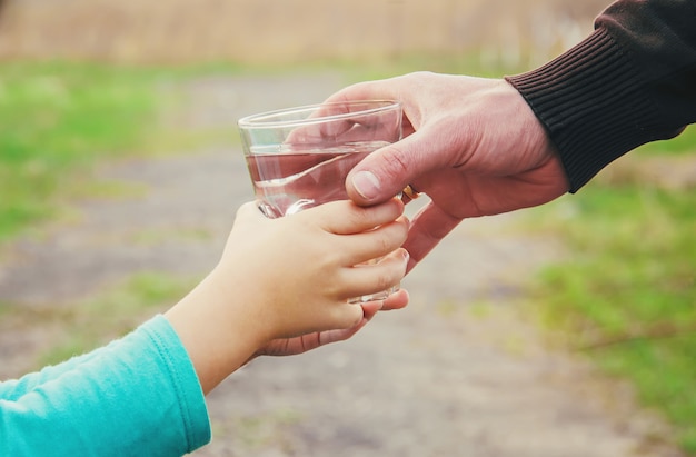 Il padre dà al bambino un bicchiere d&#39;acqua. Messa a fuoco selettiva