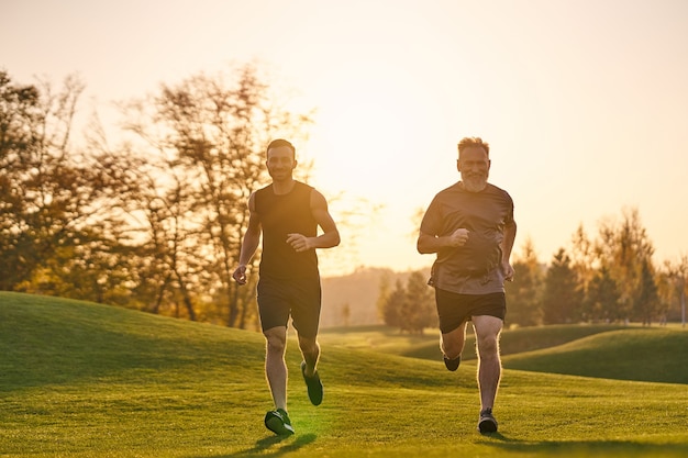 Il padre e il figlio che corrono nel bellissimo parco sullo sfondo del tramonto