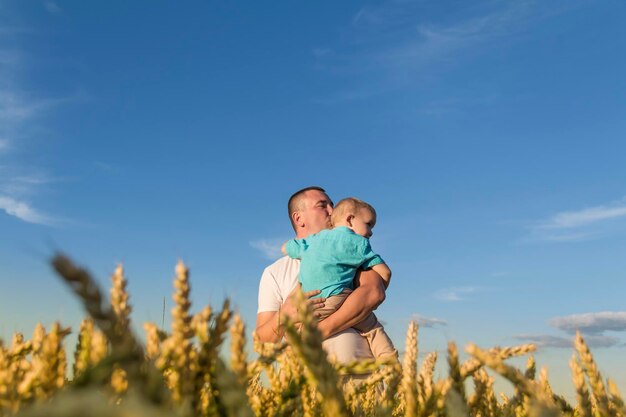 Il padre e il figlio si stanno divertendo a camminare in un campo con grano maturo Grano per fare il pane il concetto di crisi economica e fame