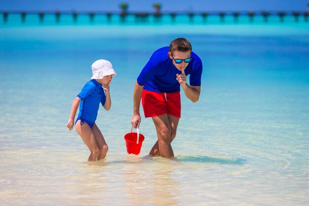 Il padre e la figlia felici si divertono sulla spiaggia tropicale