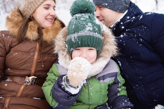 Il padre e la madre cammina con il piccolo figlio in una foresta nell'inverno.