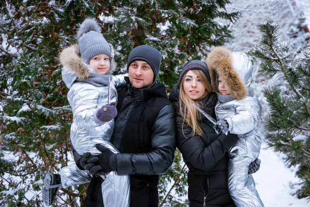 Il padre e la madre felici tengono i bambini figlio e figlia tra le braccia in una giornata invernale di neve in un nevoso ...