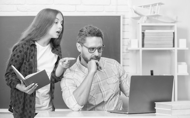 Il padre e la ragazza adolescente studiano l'insegnante privato e il bambino tengono il quaderno della famiglia aiutano papà e figlia a usare il taccuino per tornare a scuola l'educazione dell'infanzia allievo intelligente e tutor con il laptop