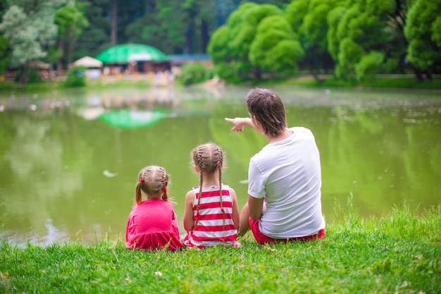 Il padre felice e le piccole figlie si rilassano sul lago