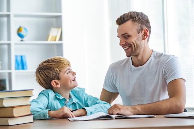 Il padre felice e un figlio che fanno i compiti alla scrivania